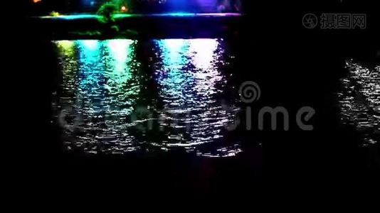 五颜六色的光在夜晚的水面上反射。视频