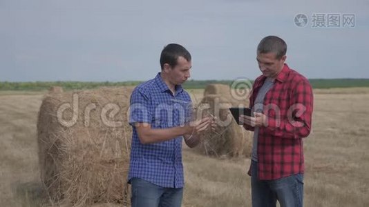 团队农业智慧农业理念.. 在数字平板电脑上研究干草堆的两名男性农民视频