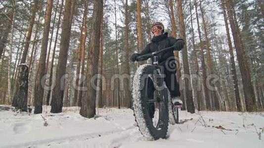 专业的极限运动员骑着一辆肥胖的自行车在户外。 骑自行车在冬天的雪林里。 人类视频