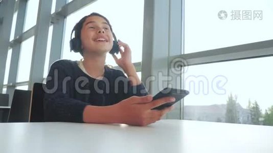 年轻快乐的十几岁女孩戴着耳机唱歌，听着智能手机上的音乐。 社会生活方式中的少女视频