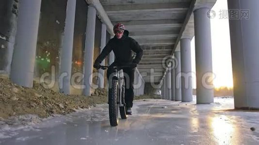 专业的极限运动员骑着一辆肥胖的自行车在户外。 骑自行车的人在冬天骑在雪冰上。 人类视频