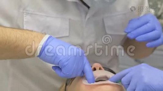 牙医在现代牙科诊所治疗病人。 正畸医生与一名助手合作。 在运作中，围堰是视频