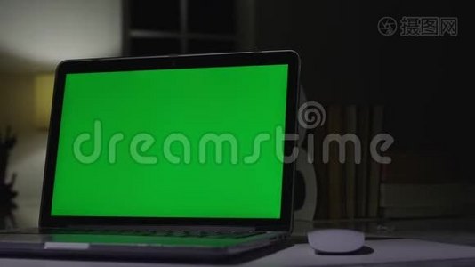 带有绿色屏幕的笔记本电脑。 黑暗的办公室。 完美地放置你自己的图像或视频。视频
