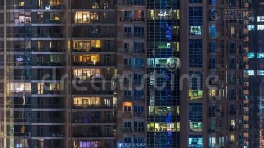 在多层现代玻璃住宅建筑的发光窗口在夜间时间推移点亮。视频