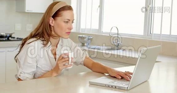 美丽的黑发女人喝咖啡，用笔记本电脑视频