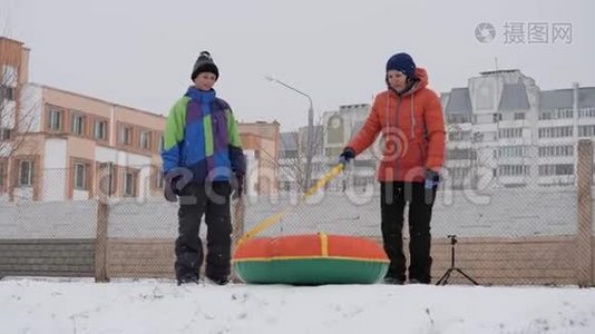 冬天的雪乐趣。 孩子们从滑梯上骑着一根管子。视频