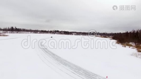 冬天，在雪覆盖的湖面上，汽车在结冰的轨道上行驶。 空中观景。 冬季雪地赛道上的赛车视频