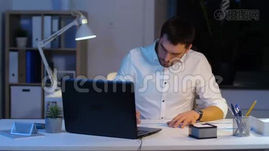 带笔记本电脑和夜间办公室文件的商人视频