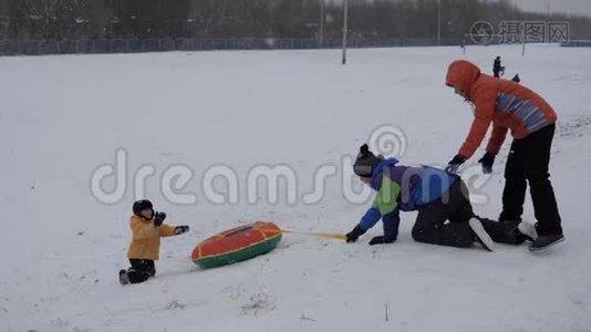 冬天的雪乐趣。 孩子们从滑梯上骑着一根管子。视频