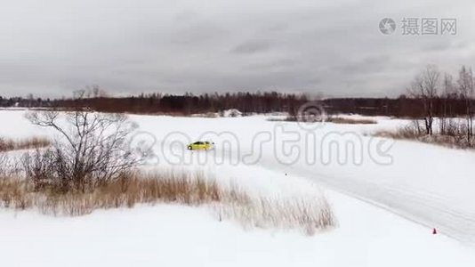 冬天，在雪覆盖的湖面上，汽车在结冰的轨道上行驶。 空中观景。 冬季雪地赛道上的赛车视频