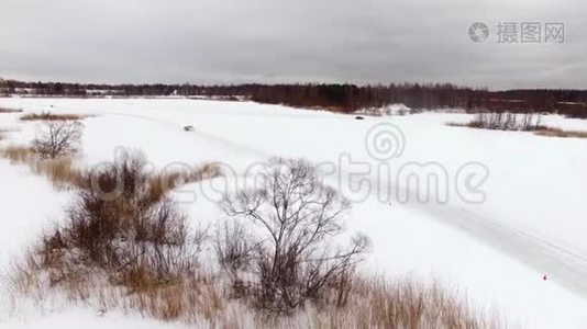 冬天，在雪覆盖的湖面上，汽车在结冰的轨道上行驶。 空中观景。 冬季雪地赛道上的赛车视频