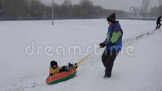 冬天的雪乐趣。 孩子们从滑梯上骑着一根管子。视频