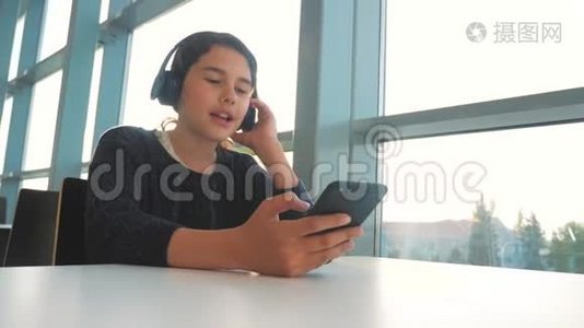年轻快乐的十几岁女孩戴着耳机唱歌，听着智能手机上的音乐。 社会中的少女生活方式视频