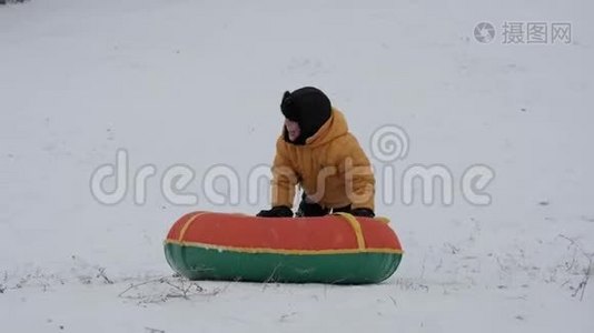 冬天的雪乐趣。 孩子们从滑梯上骑着一根管子。视频