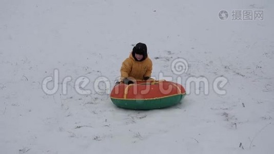 冬天的雪乐趣。 孩子们从滑梯上骑着一根管子。视频