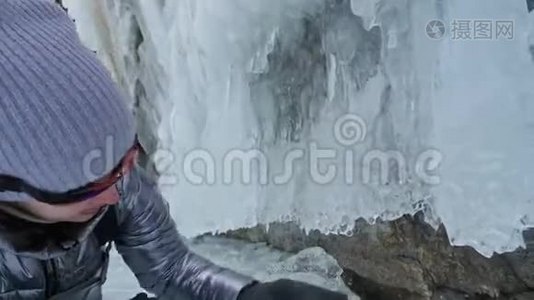 贝加尔湖冰上女子旅行。 去冬岛旅行。 女孩走在冰岩脚下。 旅行者看着视频