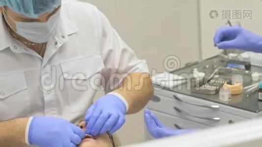 牙医在现代牙科诊所治疗病人。 正畸医生与一名助手合作。 在运作中，围堰是视频