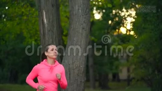 日落时分，一个女人穿过一个秋天的公园。 慢动作视频