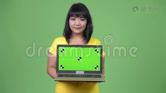 美丽快乐的亚洲女人展示笔记本电脑视频