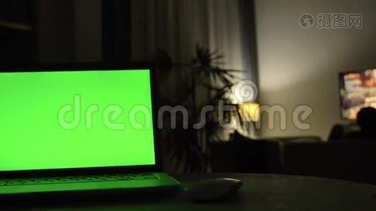 带有绿色屏幕的笔记本电脑。 黑暗的家庭办公室。视频