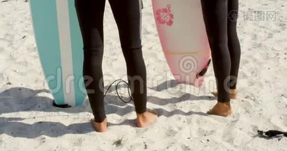 一对夫妇在海滩上站着冲浪板视频