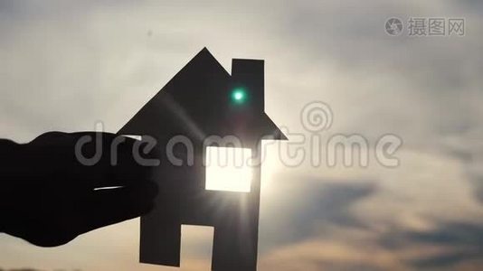 幸福家园建设理念.. 生活方式男人抱着家，手里拿着纸房子，日落时的剪影视频