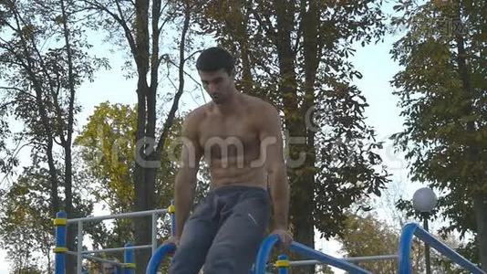 强壮的肌肉男在公园里做倒立。 适合肌肉发达的男性健身者在户外的横杠上做特技视频