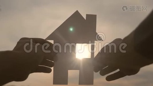 幸福家庭住宅建设理念生活方式.. 一个人手里拿着一个纸房，手里拿着夕阳的剪影视频