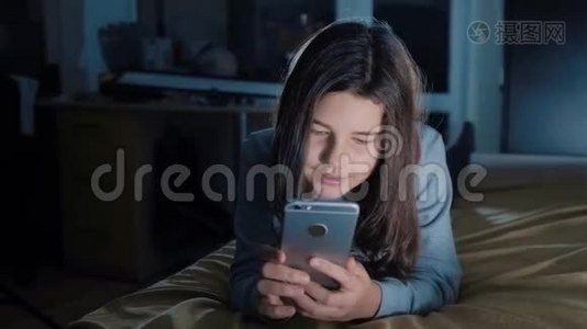 少女和智能手机。 晚上，一个小少女在社交媒体上留言聊天视频