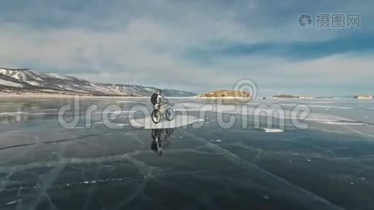 女人在冰上骑自行车。 女孩穿着银色羽绒服，自行车背包和头盔。 冰冰视频