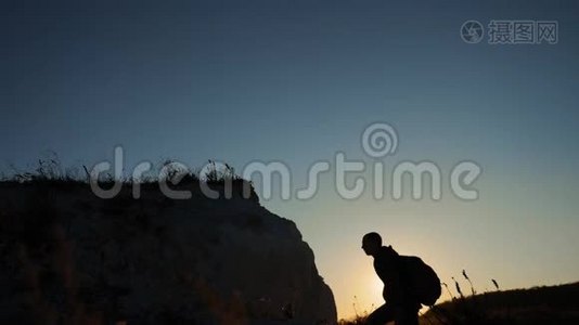 剪影游客登山者攀登一座山。 步行游客徒步旅行冒险登山者日落爬山。 慢慢慢慢视频