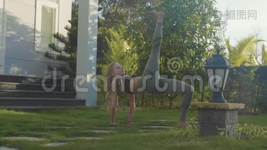 一个年轻女孩在自家后院做的体式瑜伽表演视频