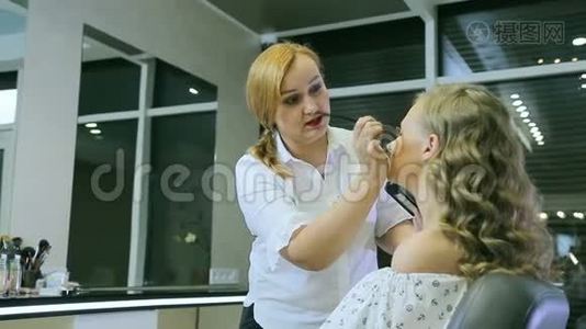 专业化妆师将色调粉末应用于金发模特眼睑。视频