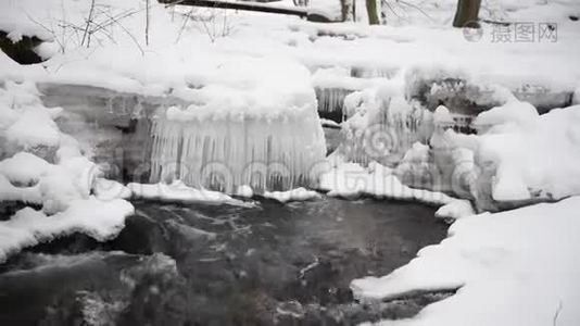 在公园里流着雪的水。 背景中的冰柱。视频