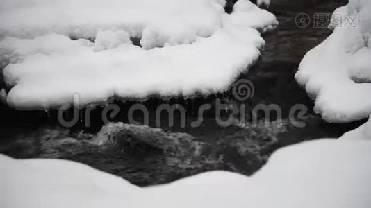 在公园里流着雪的水。 背景中的冰柱。视频