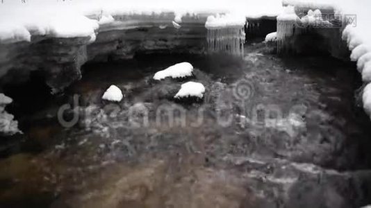 在公园里流着雪的水。 背景中的冰柱。视频