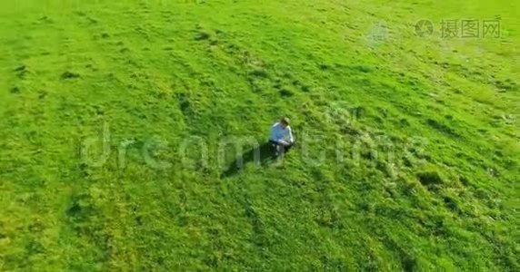 超高清4k鸟瞰图.. 低轨道飞行超过商人坐在草地上，带笔记本垫在野外视频