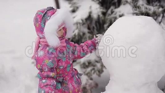 女孩在冬天的雪地里雕刻雪人。视频