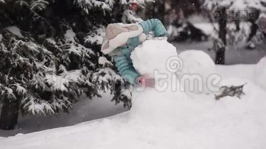 女孩在冬天的雪地里雕刻雪人。视频