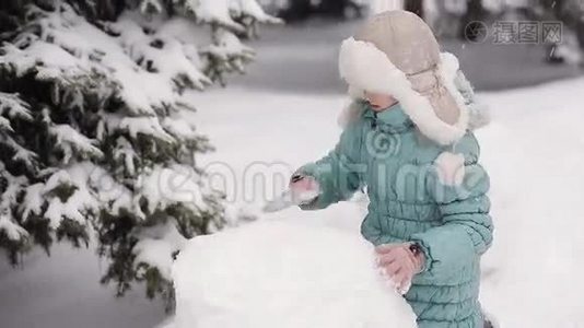 女孩在冬天的雪地里雕刻雪人。视频