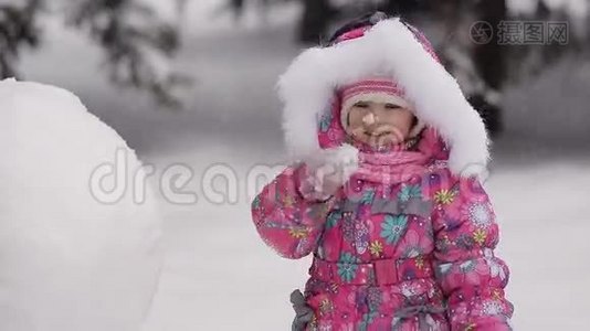 女孩在冬天的雪地里雕刻雪人。视频