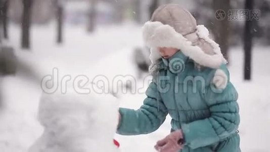 女孩在冬天的雪地里雕刻雪人。视频