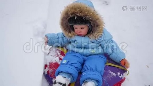 一个快乐的孩子骑在雪管上的雪山上视频