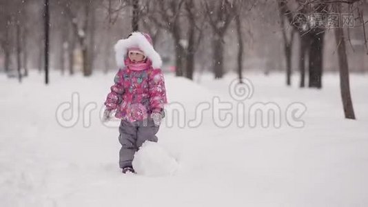 女孩在冬天的雪地里雕刻雪人。视频