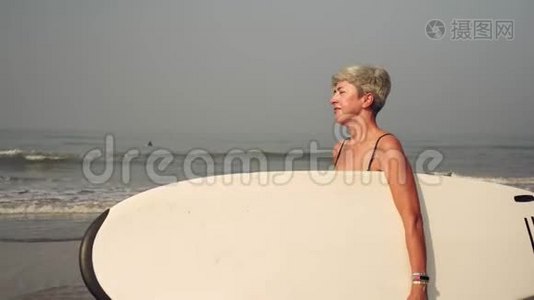 奶奶，沙滩上成熟的女人拿着冲浪板视频