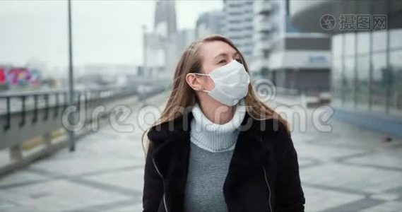 COVID-19流行病保护。 年轻的金发女郎戴着医用口罩，在封锁期间沿着空城街道散步。视频