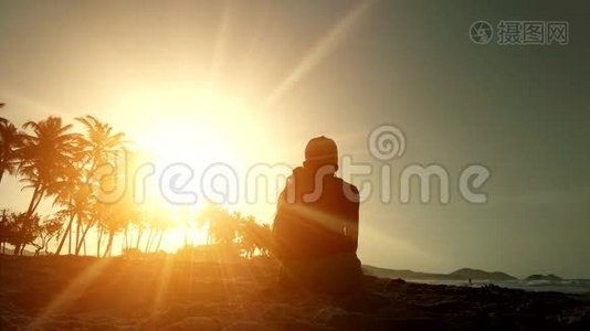 一个快乐女孩的剪影在日落时抛出沙子。 幸福和好运的概念..视频