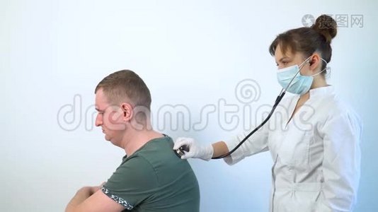 在医院的一次医疗检查中，使用听诊器的女医生听病男病人的肺。 健康视频