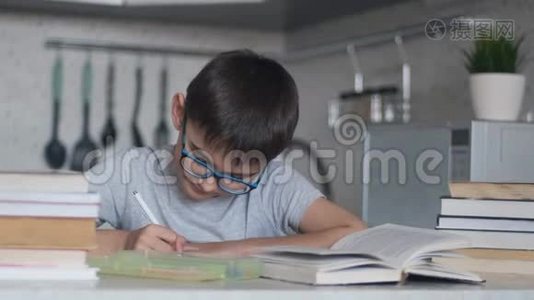 一个男孩用许多教科书和书做家庭作业。 摄像机向右移动视频