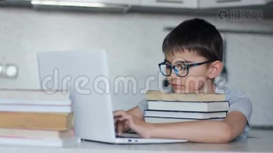 有魅力的男生在餐桌旁坐在厨房里做作业，用大量的课本和笔记本电脑视频